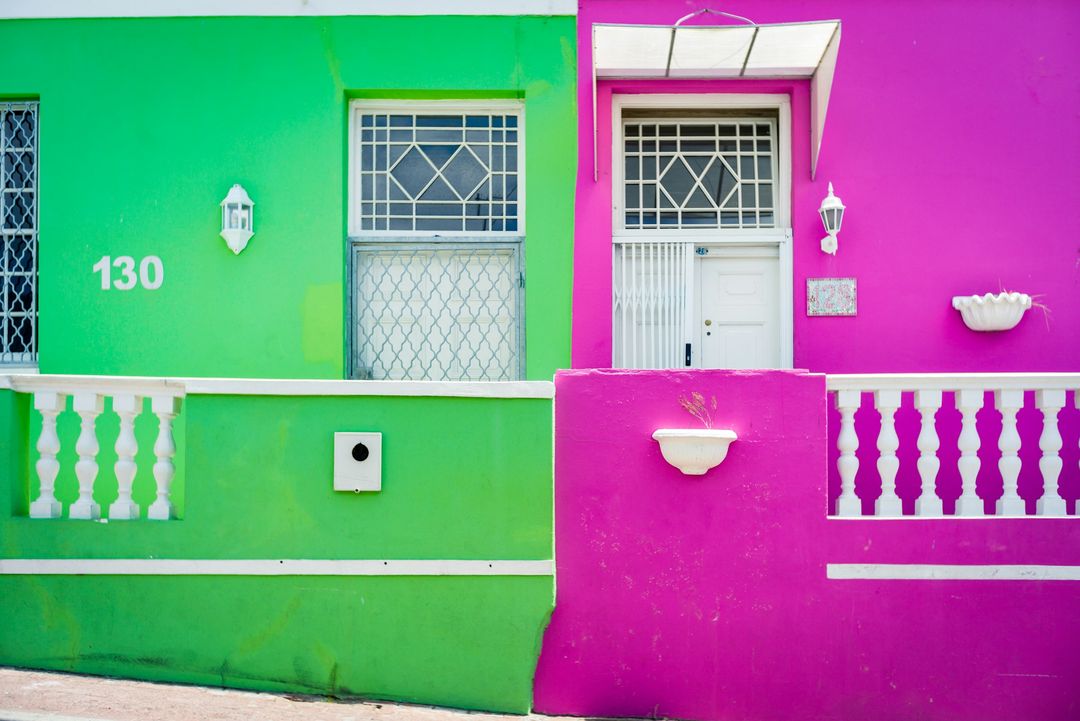 A bright green house beside a magenta one with white balustrades