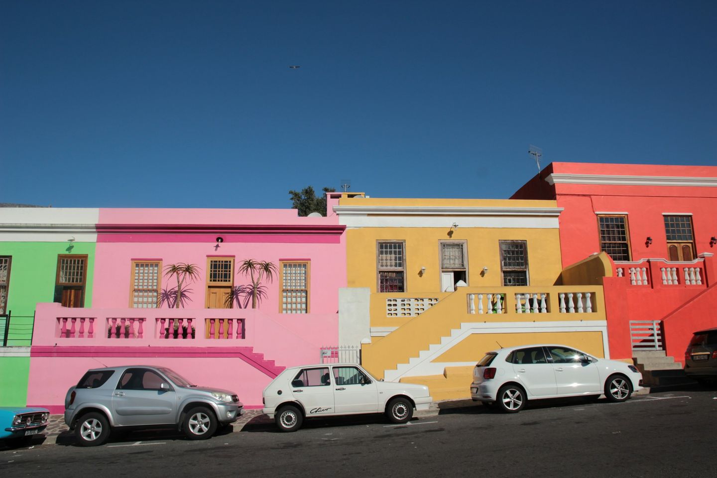 A row of pink, yellow and coral houses under a deep blue sky