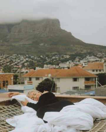 Asleep in white bedding on the rope-net deck, Table Mountain behind
