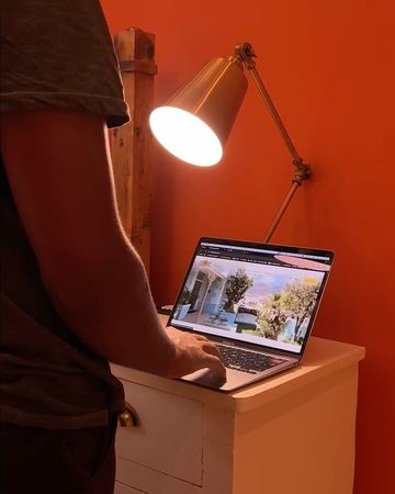 Working on a laptop under a brass lamp in the orange room