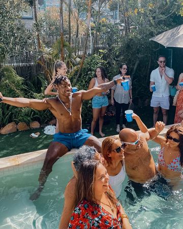 A pool party: guests laughing and dancing in and around the pool