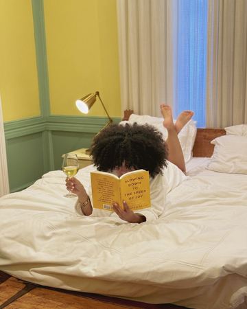 Reading in bed in the yellow room with a glass of wine