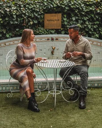 A couple sharing a pot of tea at the iron table by the wishing well