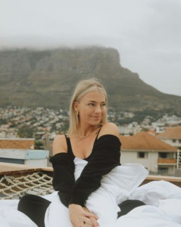 Wrapped in white bedding on the rope-net deck, Table Mountain under cloud behind