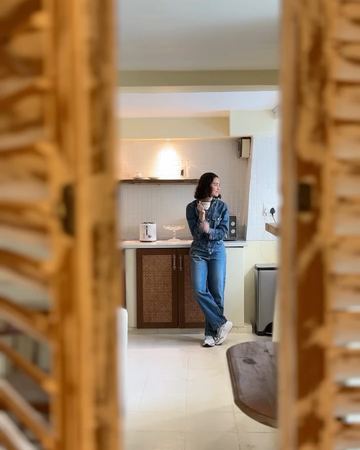 A cup in hand in the kitchenette, seen between the wooden shutters