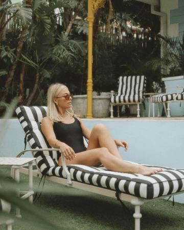 Stretched out in sunglasses on a striped lounger by the pool