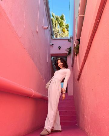 A guest in pale pink on a narrow stairway between pink walls