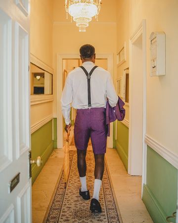 A guest in a white shirt and braces walking down the hallway under the chandelier