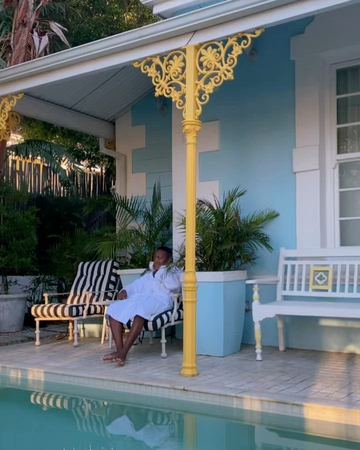 A guest in a robe on a lounger on the verandah by the pool