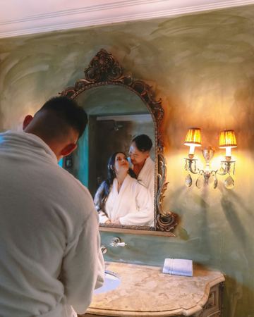 A couple in robes at the ornate bathroom mirror