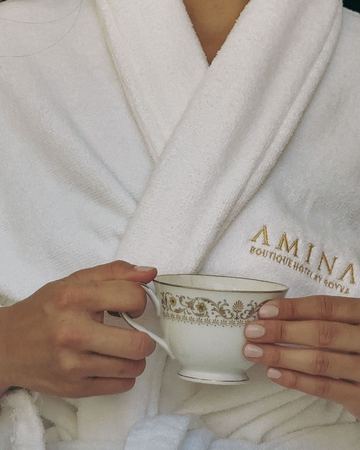 A china teacup held against the embroidered Amina robe
