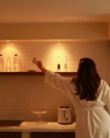 Reaching for a cup in the warm light of the kitchenette