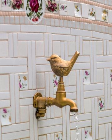 A brass bird tap on the wishing well's mosaic