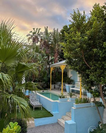 The garden, the pool and the verandah corner under a pastel sunset sky