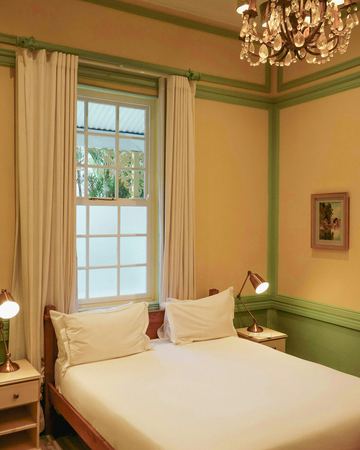 The yellow and green room: the bed, the chandelier and the sash window