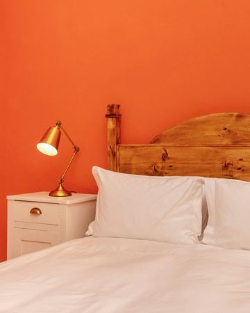 The orange room: the pine headboard and the brass lamp