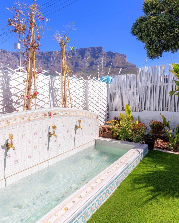 The wishing well in the garden with its brass bird taps, Table Mountain behind