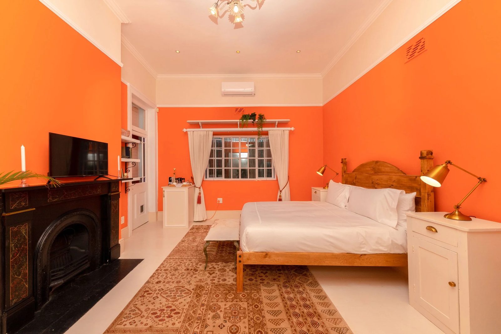Room 3: warm orange walls, a black fireplace, a pine bed and a Persian rug
