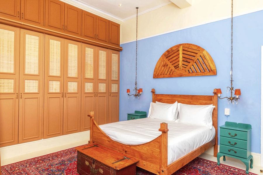 The blue room: the carved fan above the bed, the wall of wooden wardrobes and a red rug