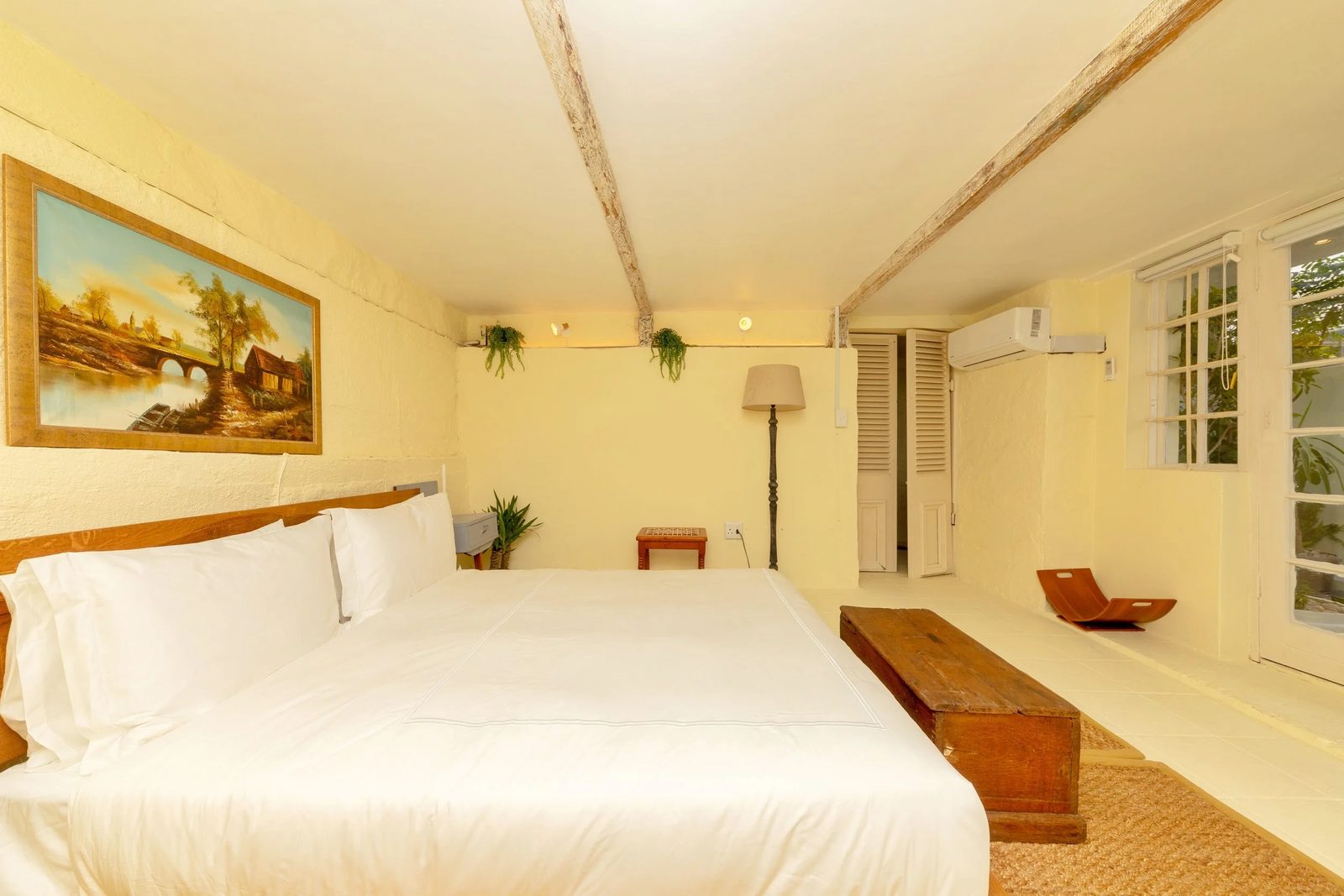 Room 5, the Bungalow Suite: cream walls, timber beams, a queen bed and a landscape painting